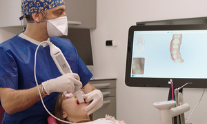 Zahnarzt verwendet Intraoralscanner zur Erfassung der Mundhöhle, Bildschirm zeigt 3D-Modell der Zähne. Technologien: Triangulation, Mikroskopie.
